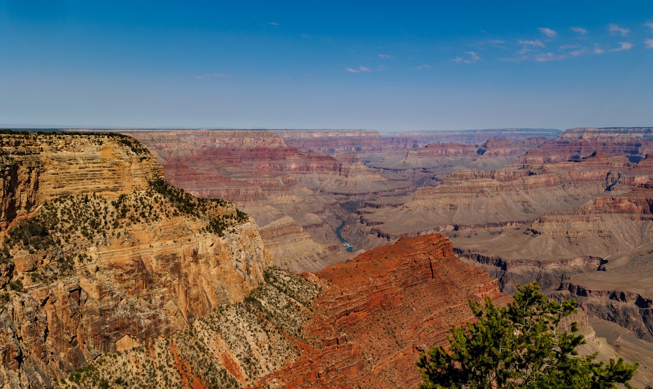 discover Breathtaking panoramic view of Grand Canyon's dramatic cliffs and valleys under clear skies.