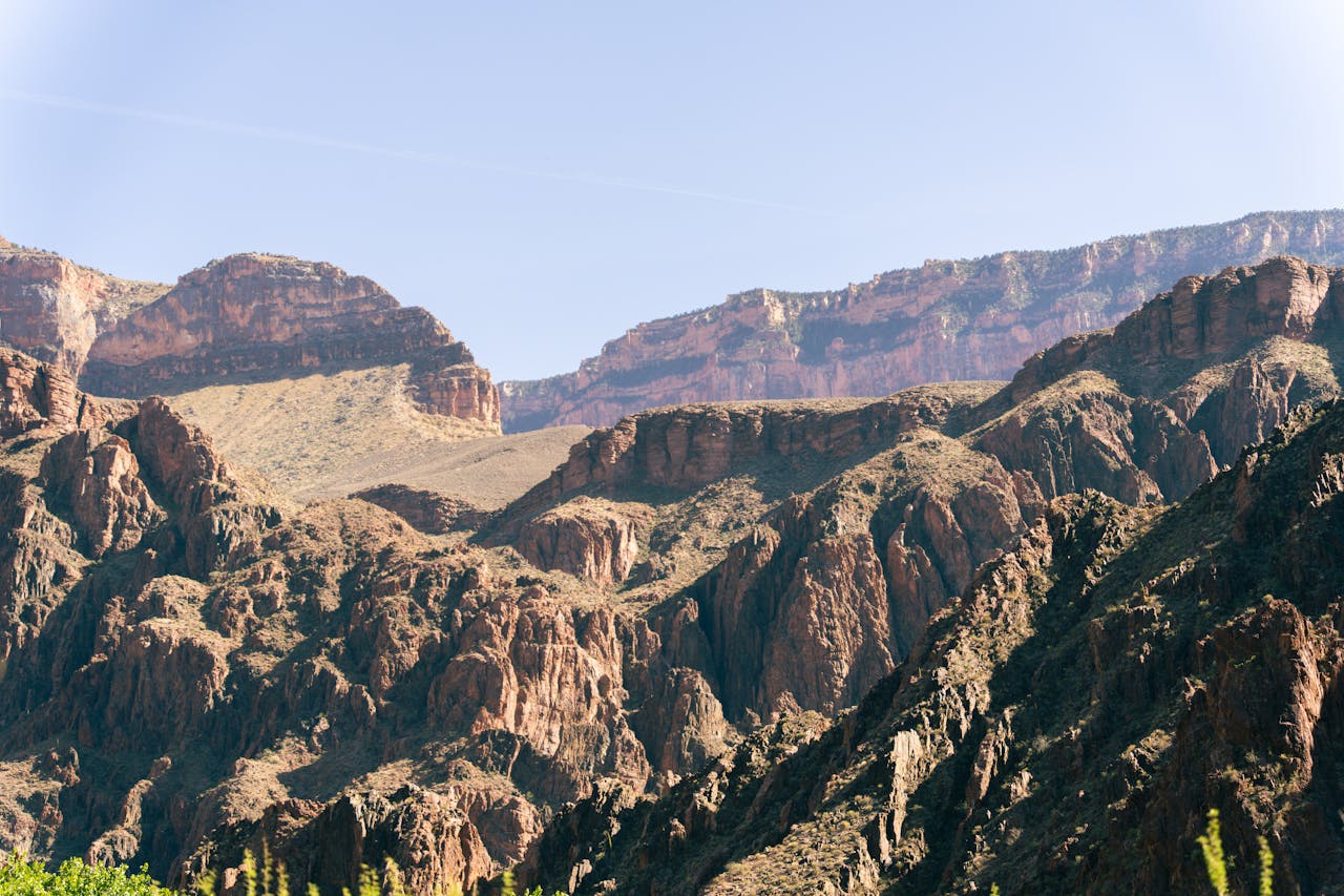 services-04 Stunning view of the rugged Grand Canyon cliffs under a clear blue sky, perfect for nature enthusiasts.
